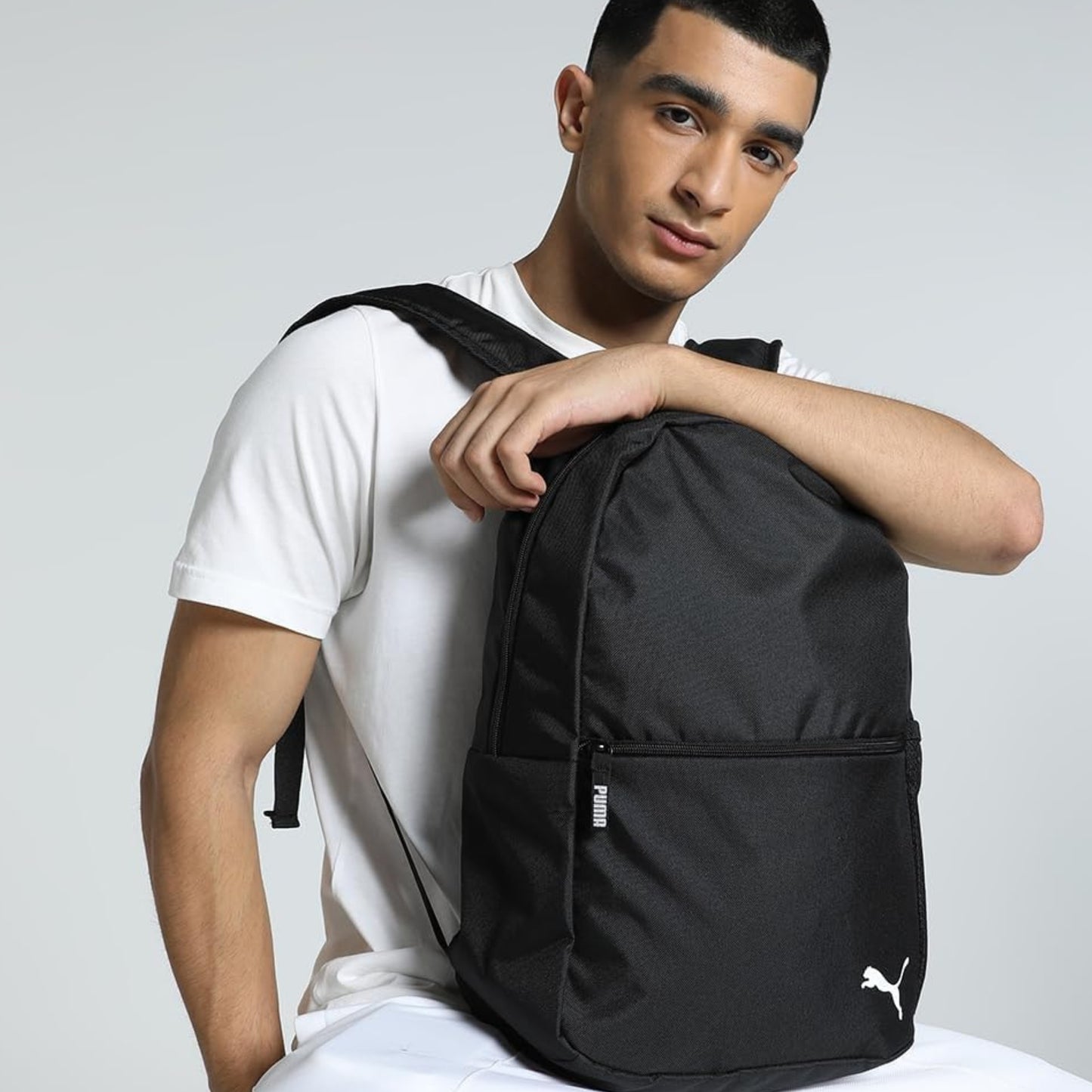 Man wearing a black Puma backpack against a plain background