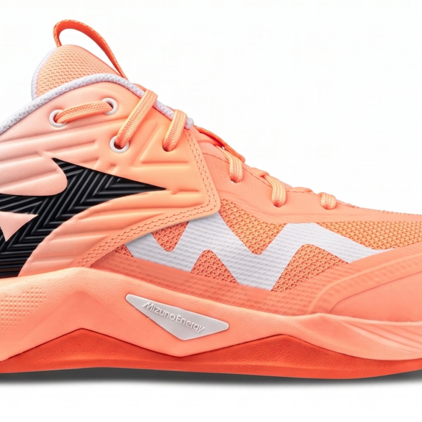 A close-up side view of a Mizuno squash shoe in a vibrant coral orange colorway, featuring a black zigzag side stripe, a white zigzag pattern on the side, and a silver MizunoEnergy logo on the midsole.