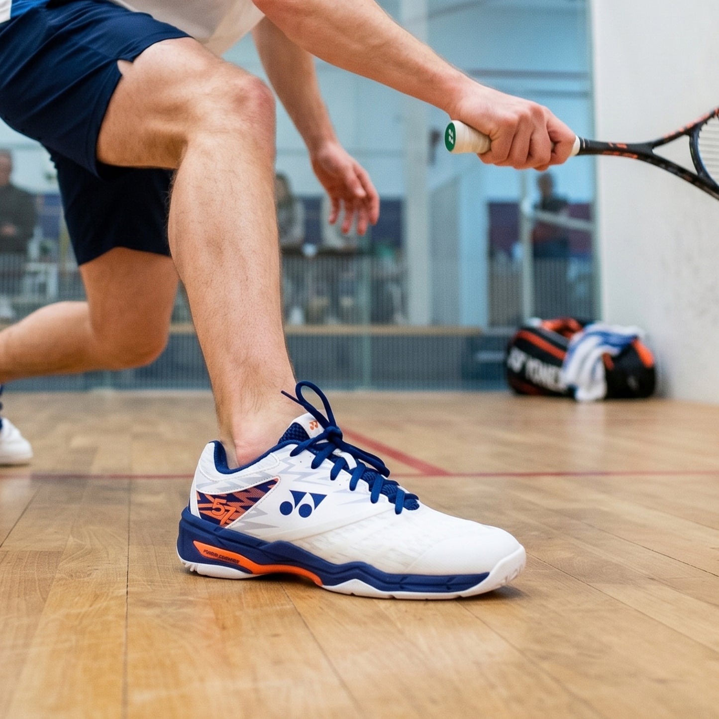 Person playing squash with focus on white and blue athletic shoe