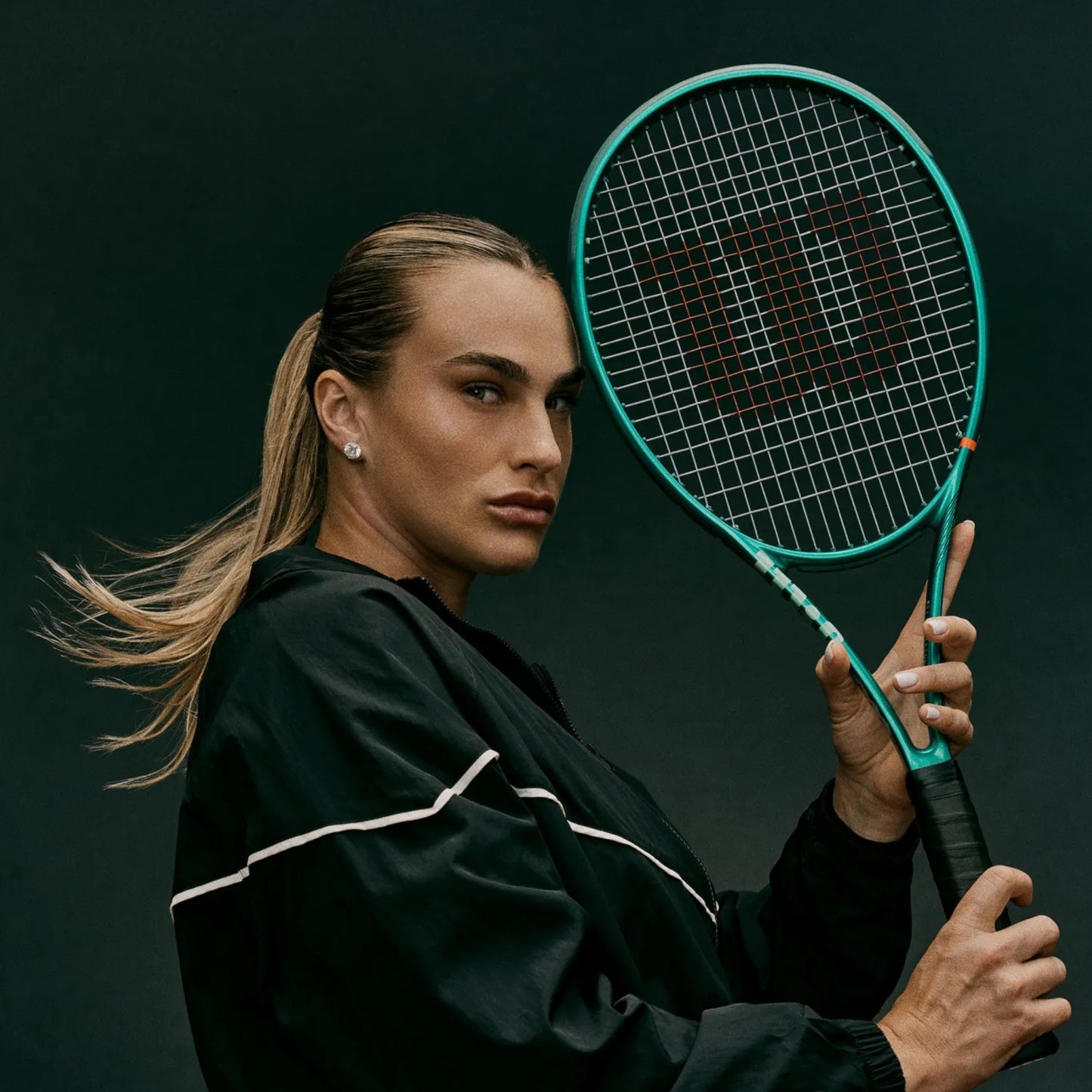 Person holding a tennis racket against a dark background