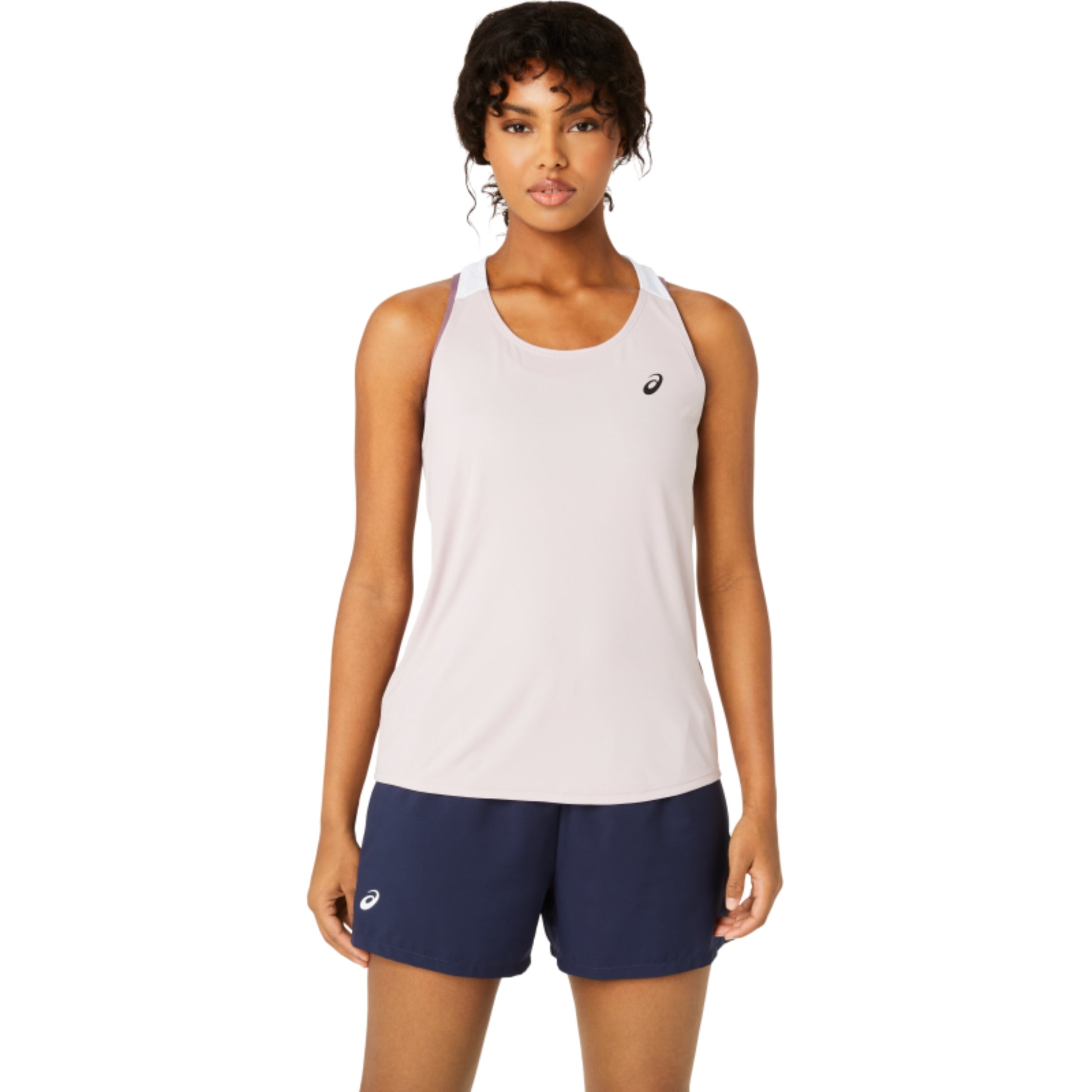 Woman wearing a light rose Asics tank top and navy shorts with a brand logo on a white background