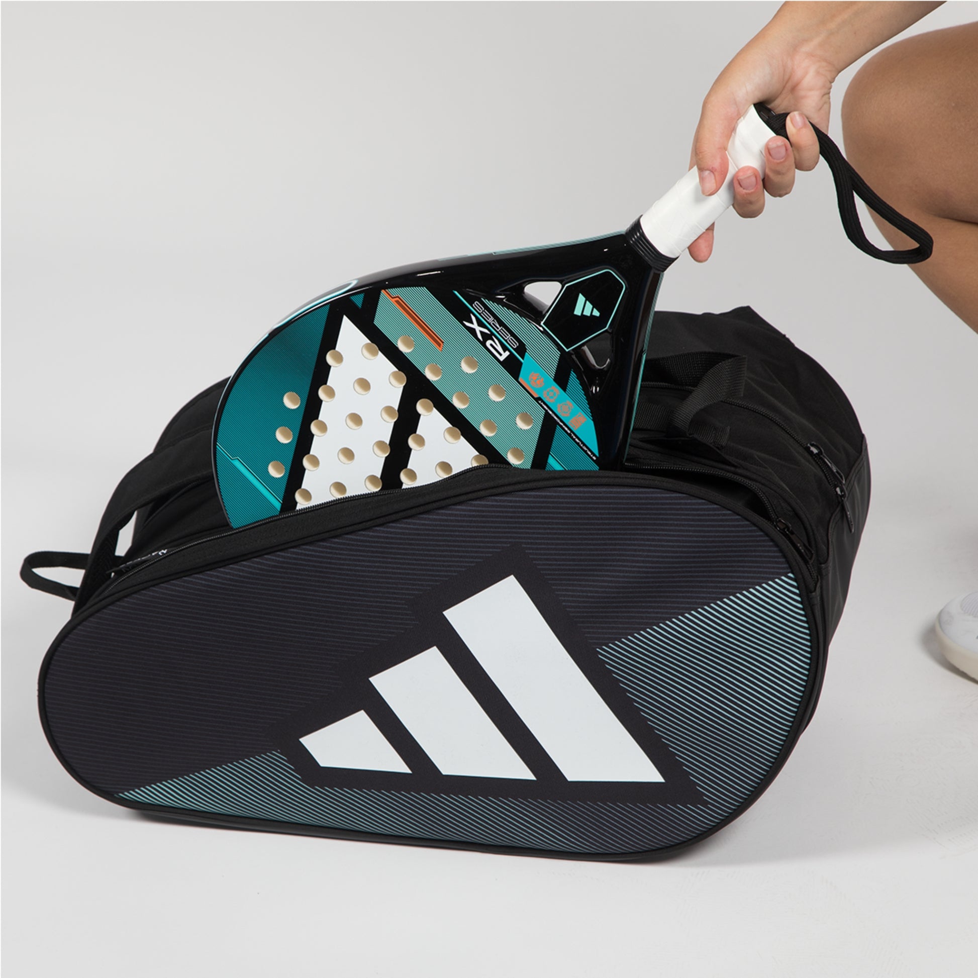 Paddle and racket in a black Adidas bag on a light gray background
