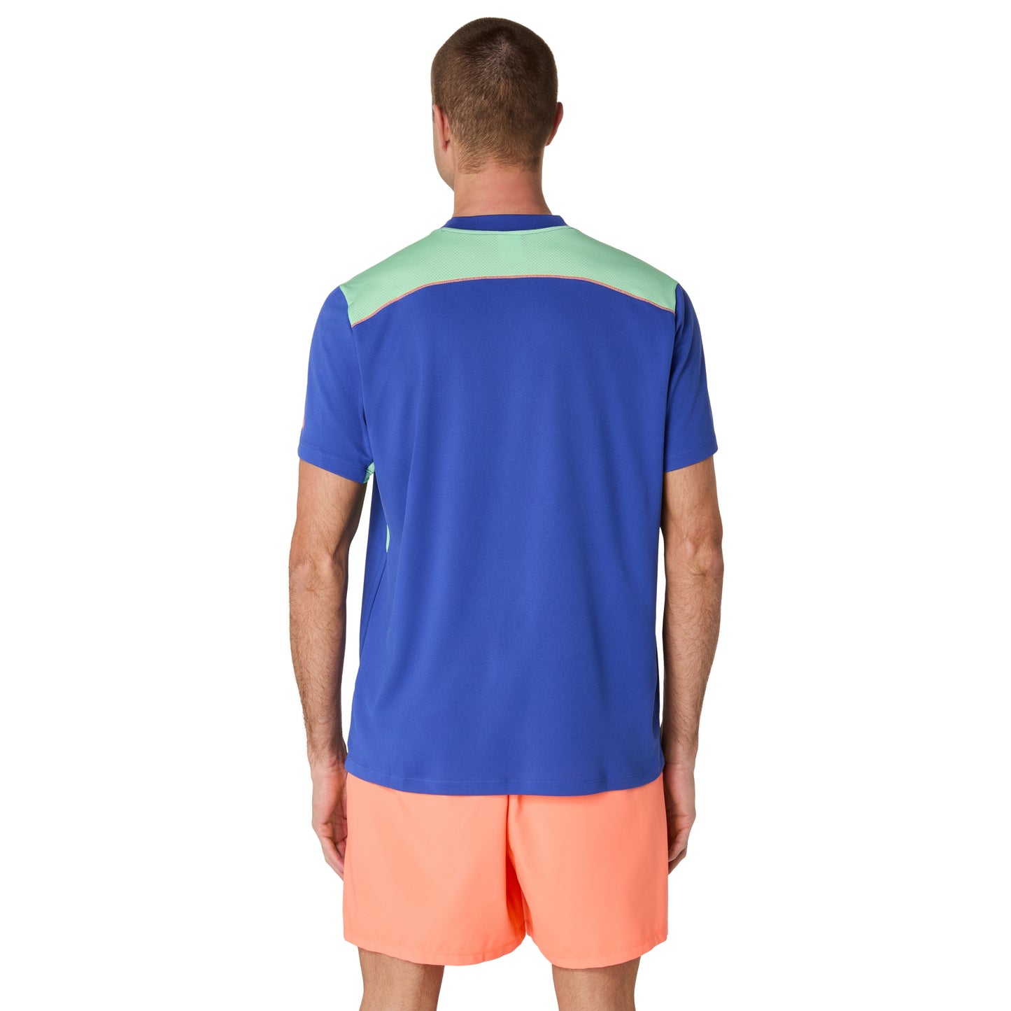 Man wearing a blue and green sports shirt with orange shorts on a white background