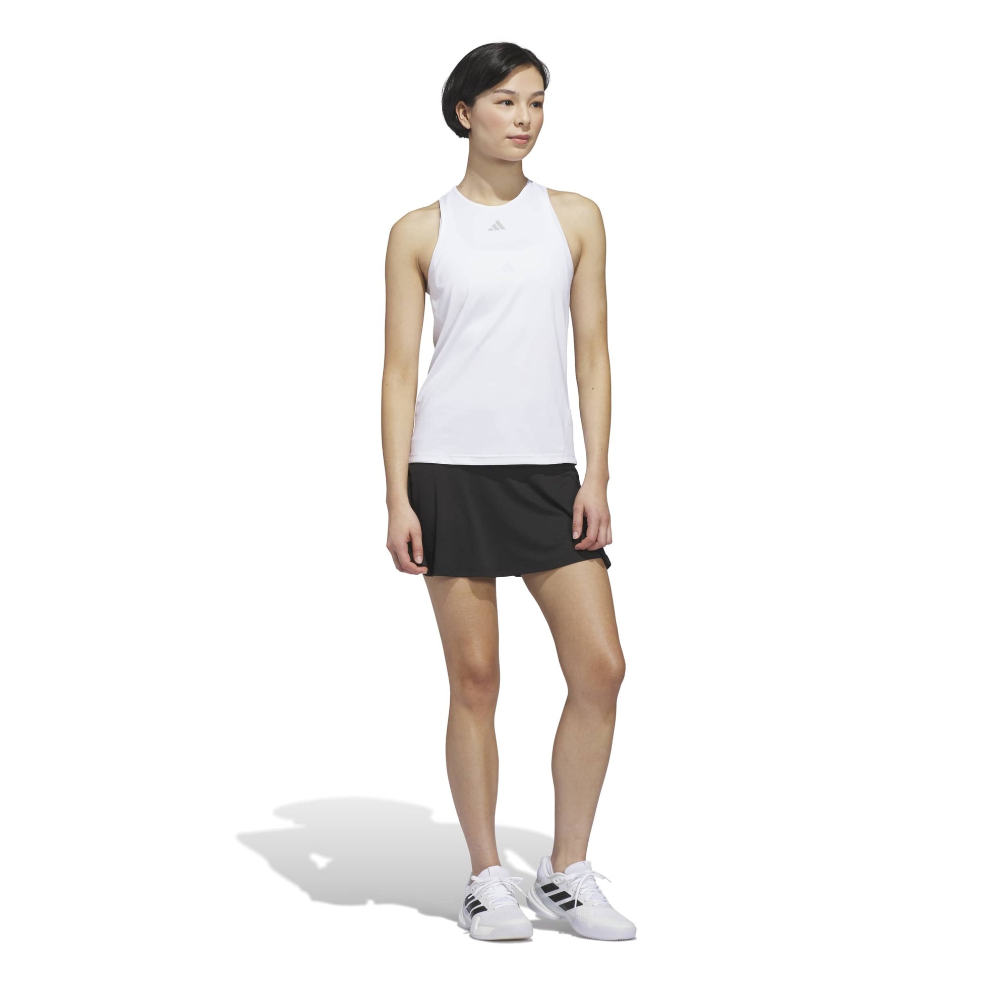 Woman wearing a white sleeveless adidas top with a logo on a white background