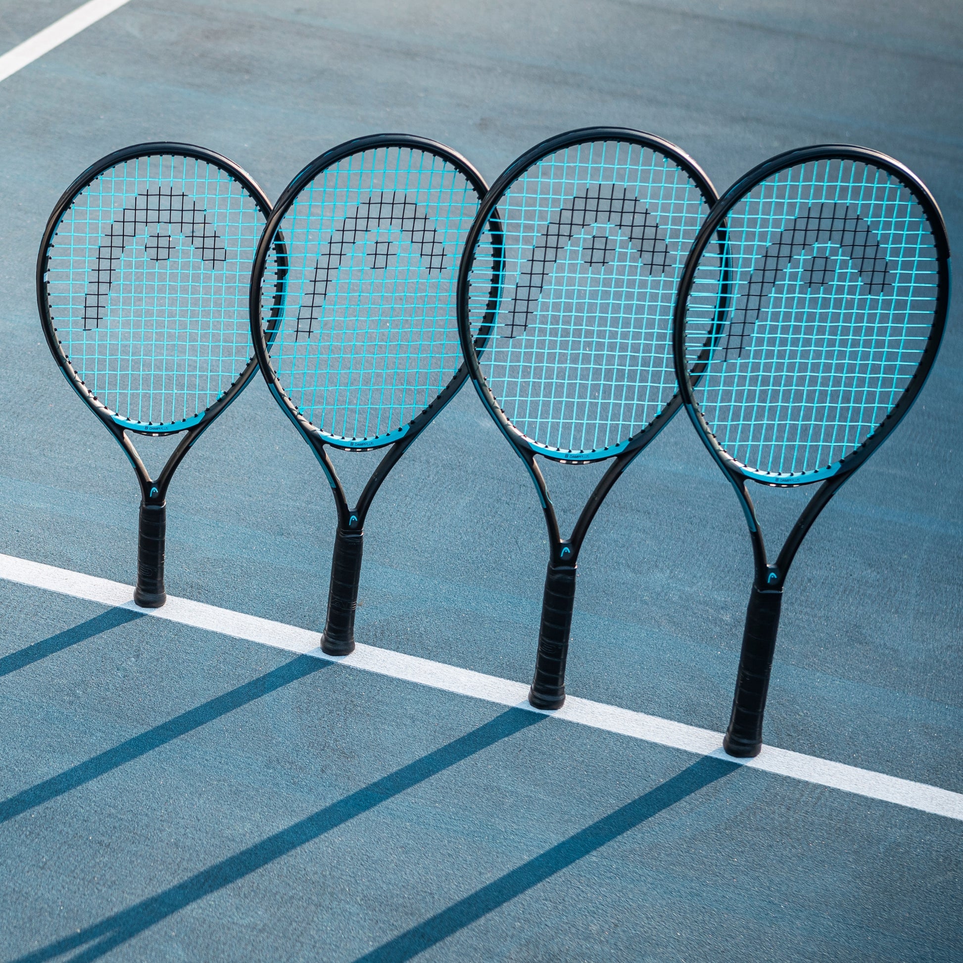 Four tennis rackets with blue strings on a tennis court