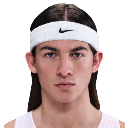Person wearing a white Nike headband on a white background