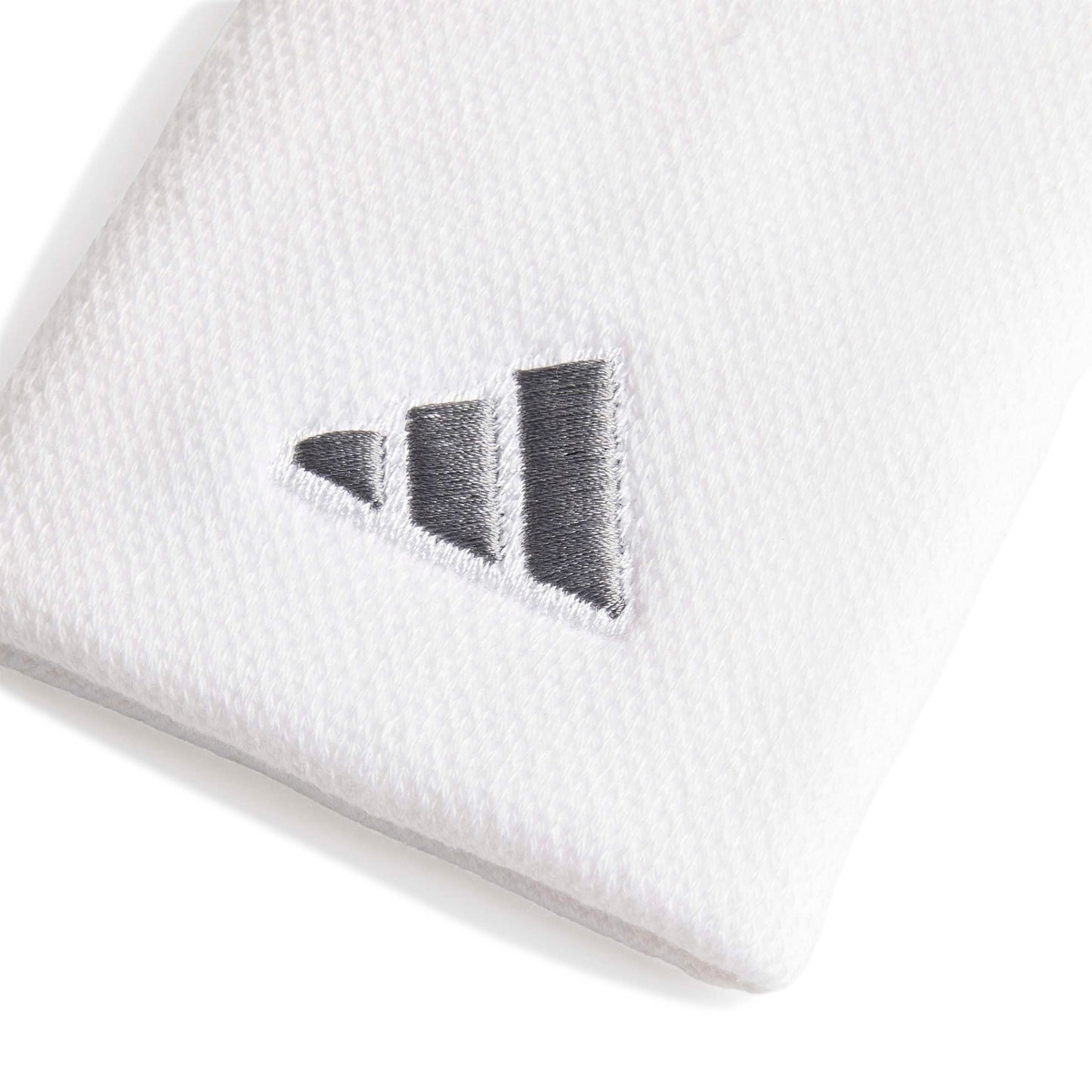 A close-up of a white wristband accessory featuring a dark gray embroidered Adidas logo.