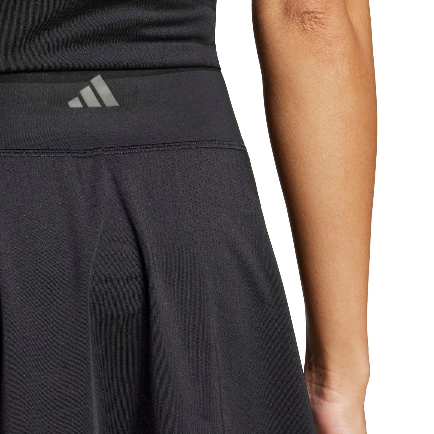 A woman wearing a black adidas skirt on a white background