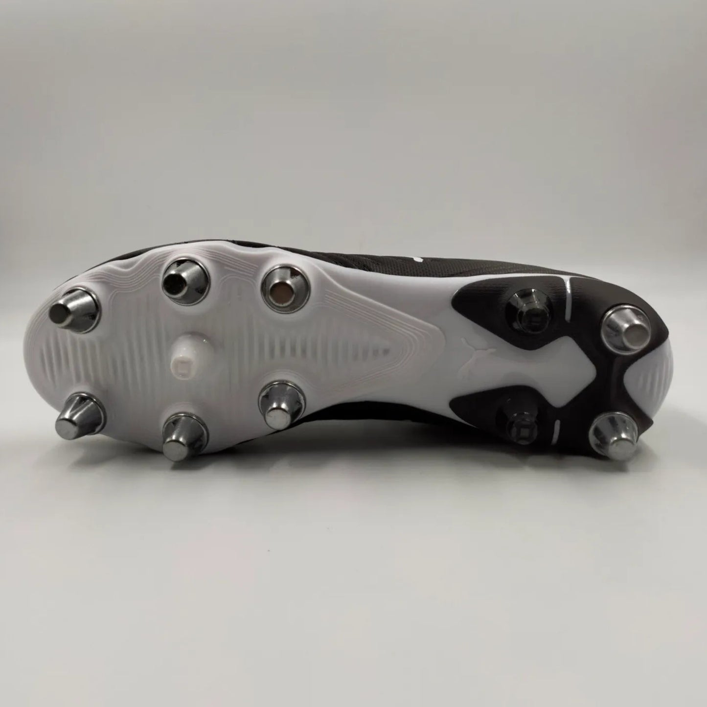 Close-up of a rugby boot with metal studs on a gray background