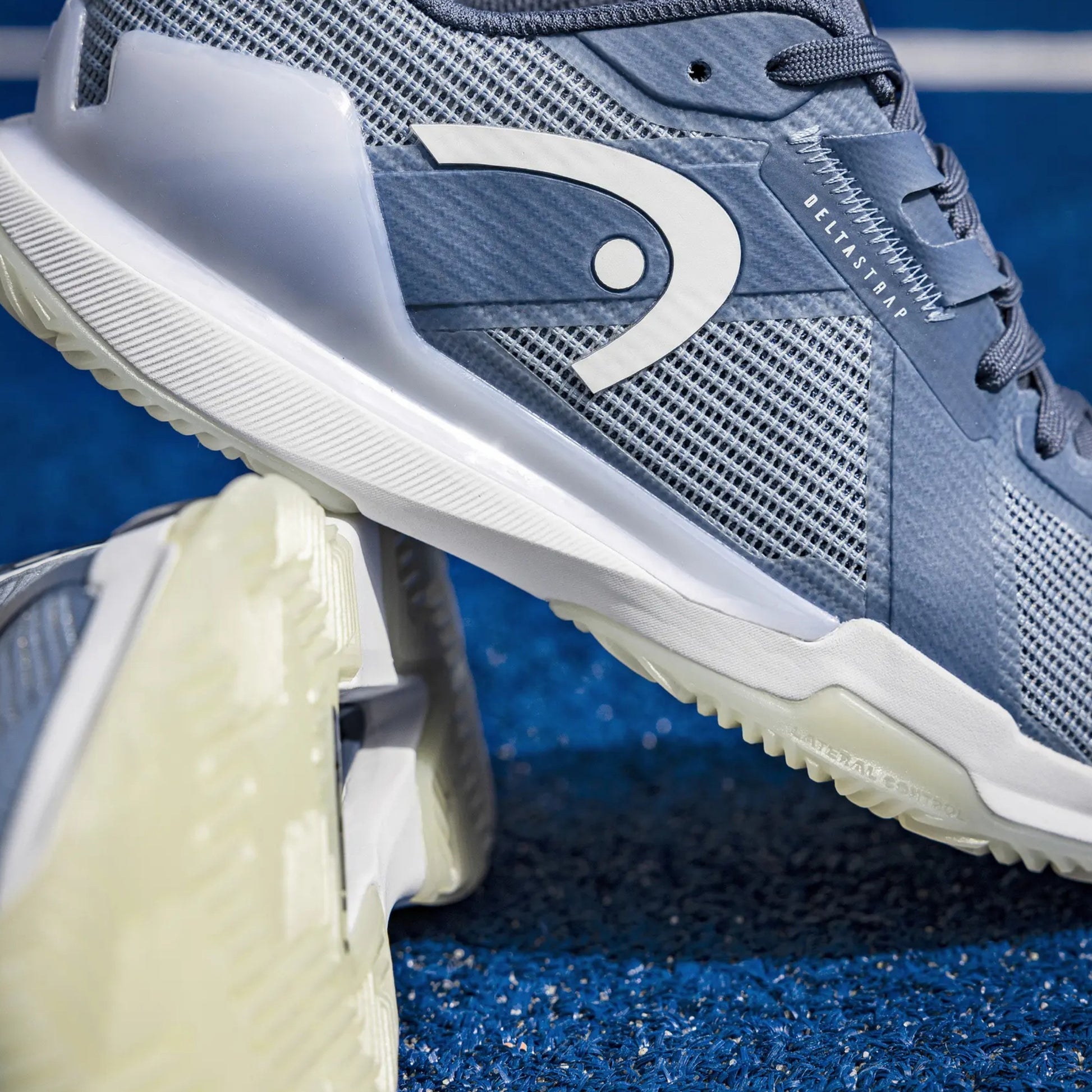 Blue Head padel shoe with white sole on a blue textured background