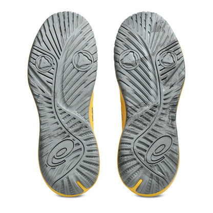 The outsoles of a pair of Asics tennis shoes, showing a textured gray design with yellow accents along the edges, photographed against a solid white background.