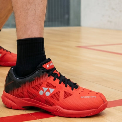 Red and black athletic shoe on a wooden floor