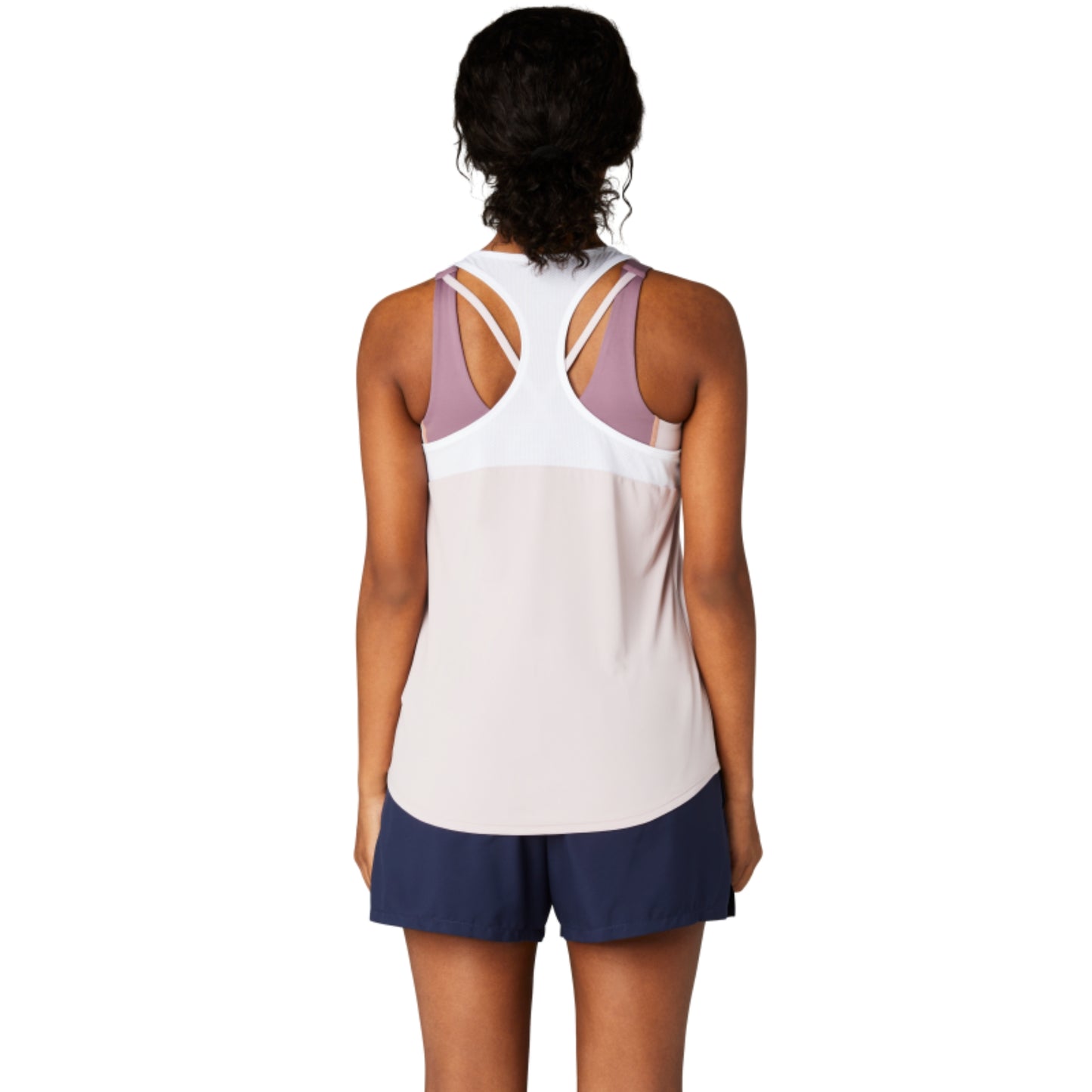 Person wearing a light rose tank top with thin straps and navy shorts on a white background