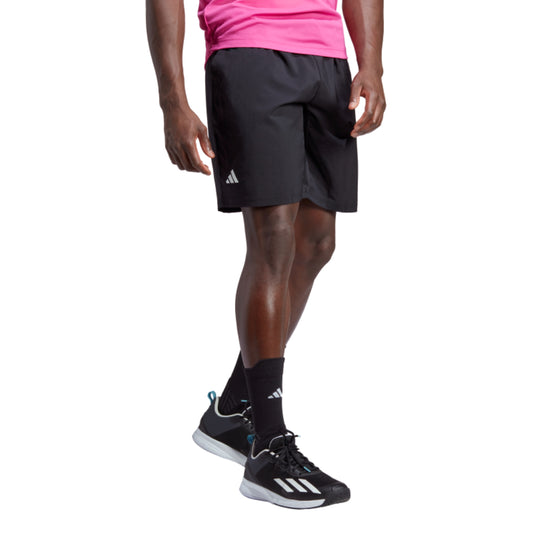 Person wearing black Adidas shorts and shoes on a white background