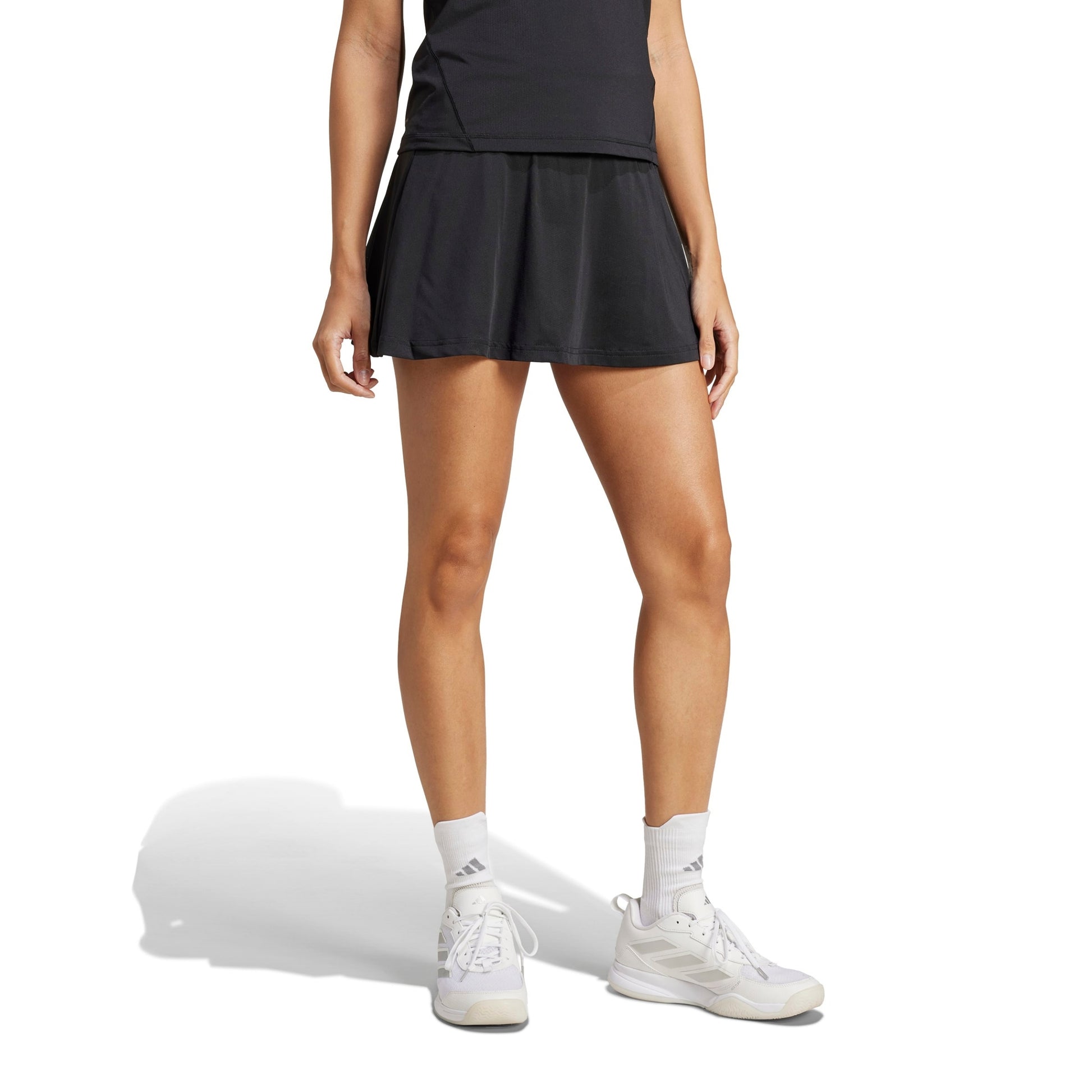 A woman wearing a black adidas skirt on a white background