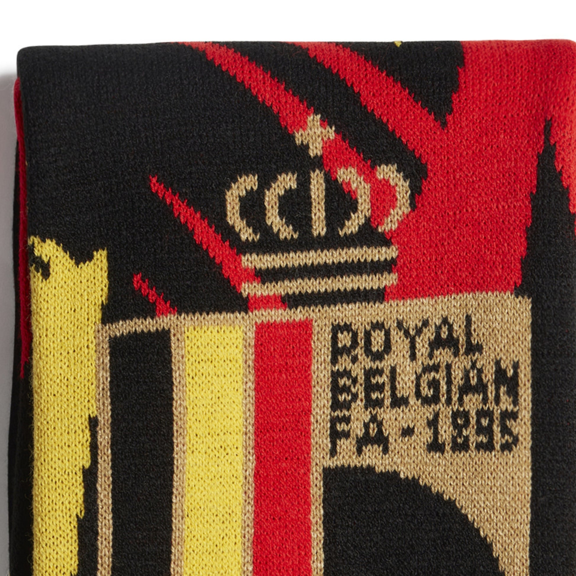 Close-up of a scarf with a logo and text, featuring red, black, yellow, and beige colors.
