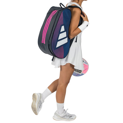 Person holding a blue and pink Adidas tennis bag with a white background