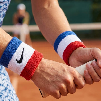 Person holding a tennis racket with Nike wristbands on a tennis court