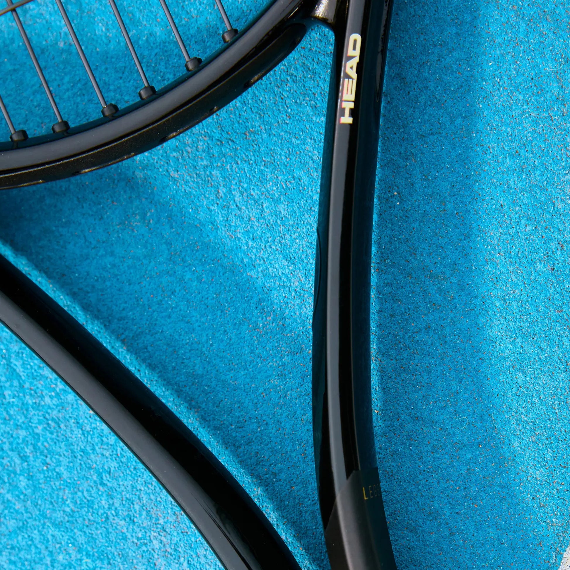 Close-up of a tennis racket with 'HEAD' branding on a blue background