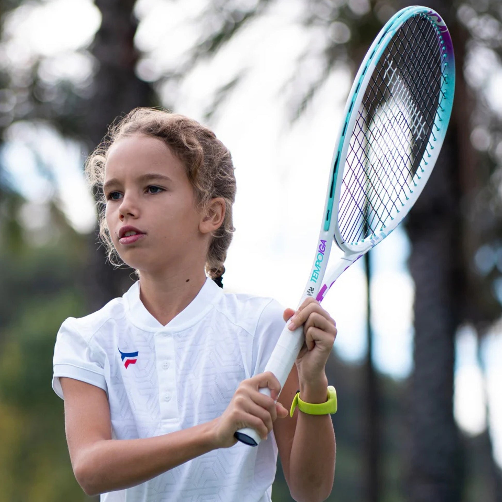 Child holding a tennis racket with a blurred outdoor background