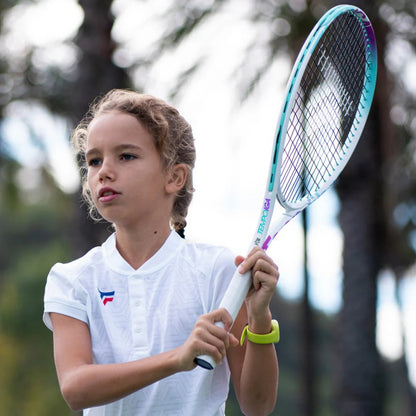 Child holding a tennis racket with a blurred outdoor background