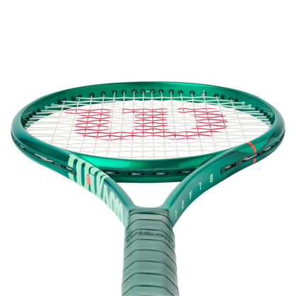 Tennis racket with green frame and white strings on a white background