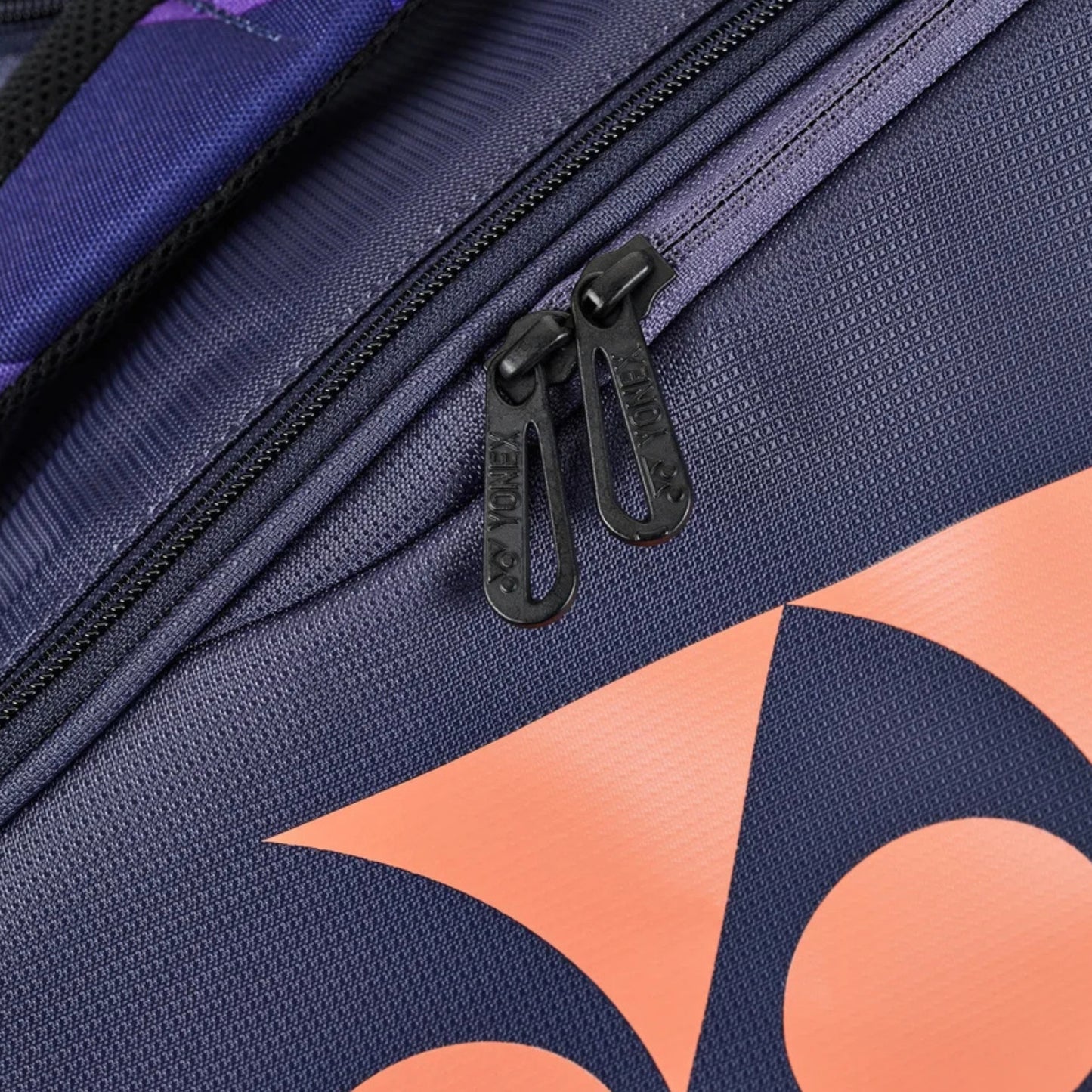 Close-up of a Yonex tennis racket bag with orange geometric patterns and a black zipper.