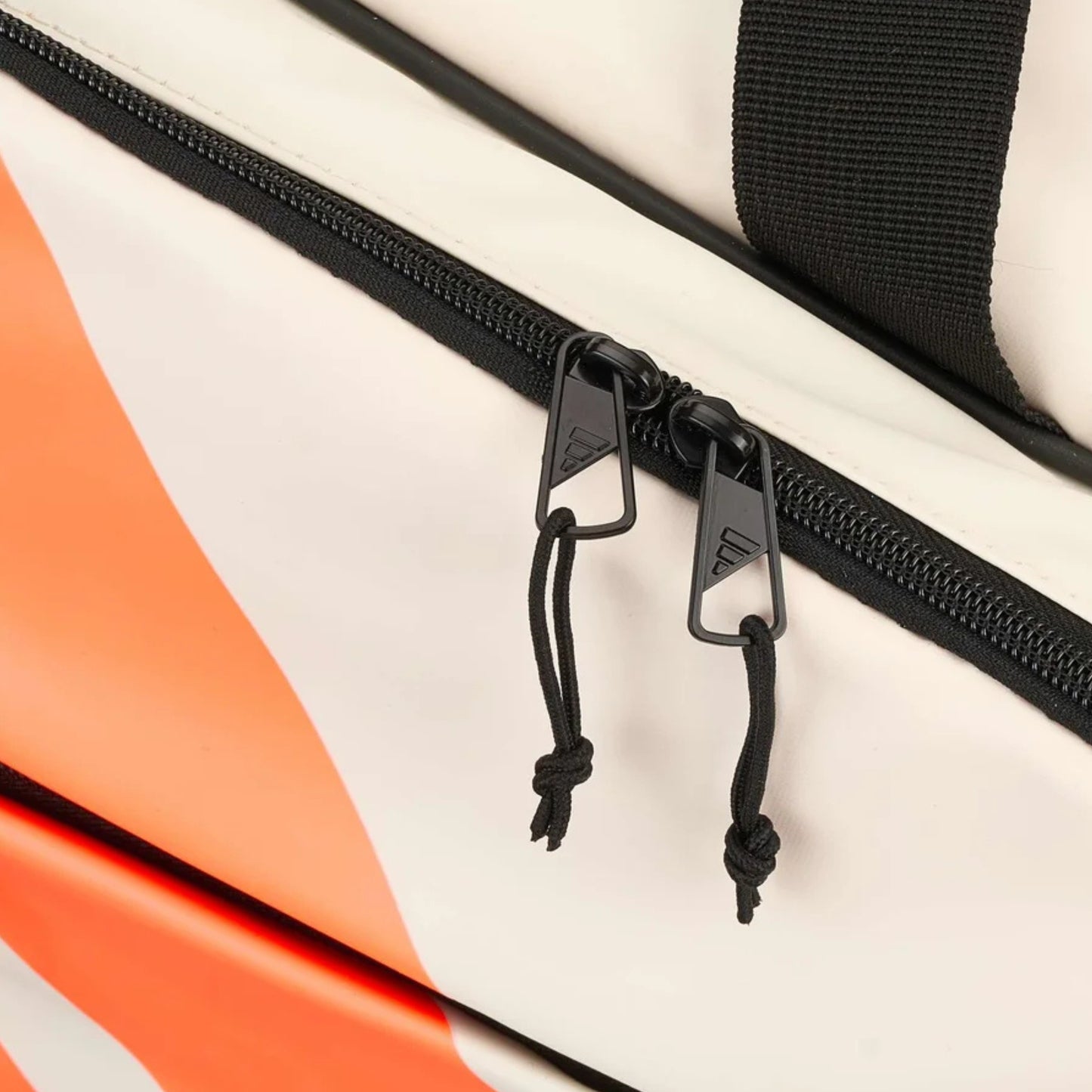 Close-up of a black zipper on a tennis bag with orange and white design.