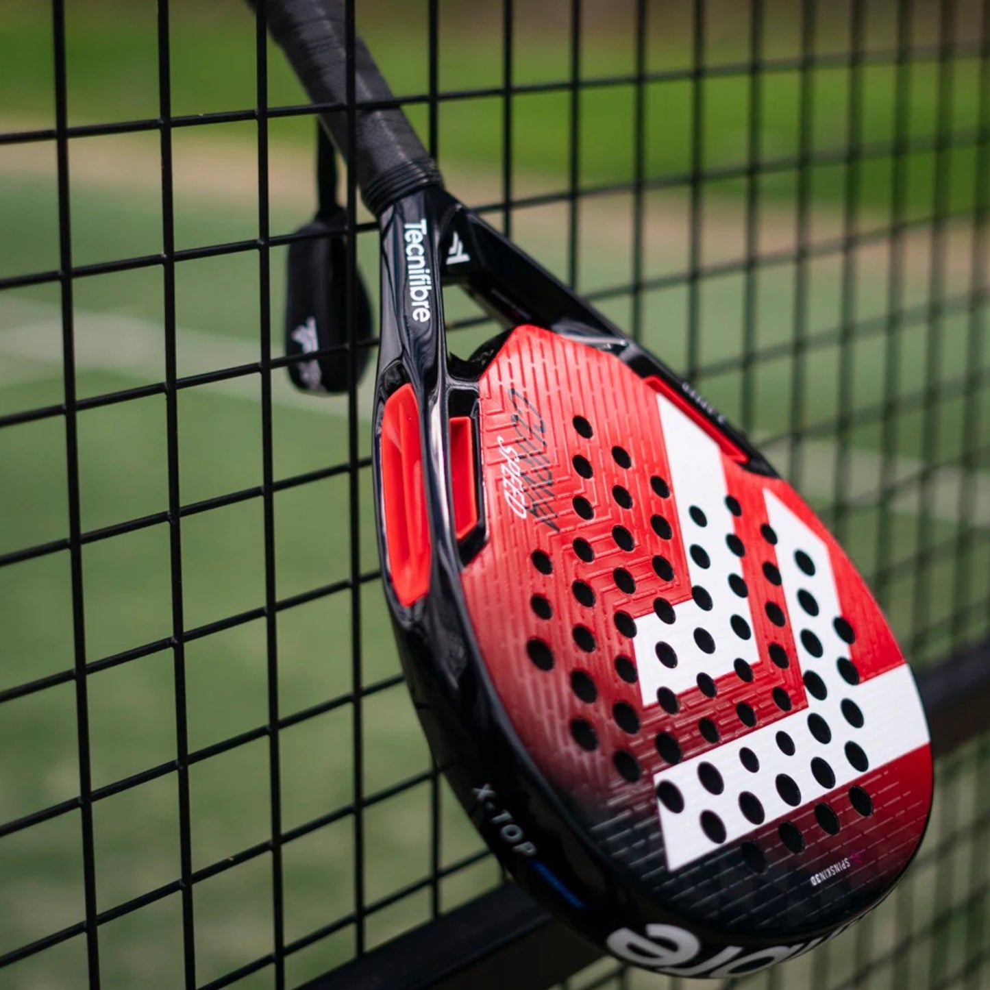 Red and black padel racket with brand logo on a red background