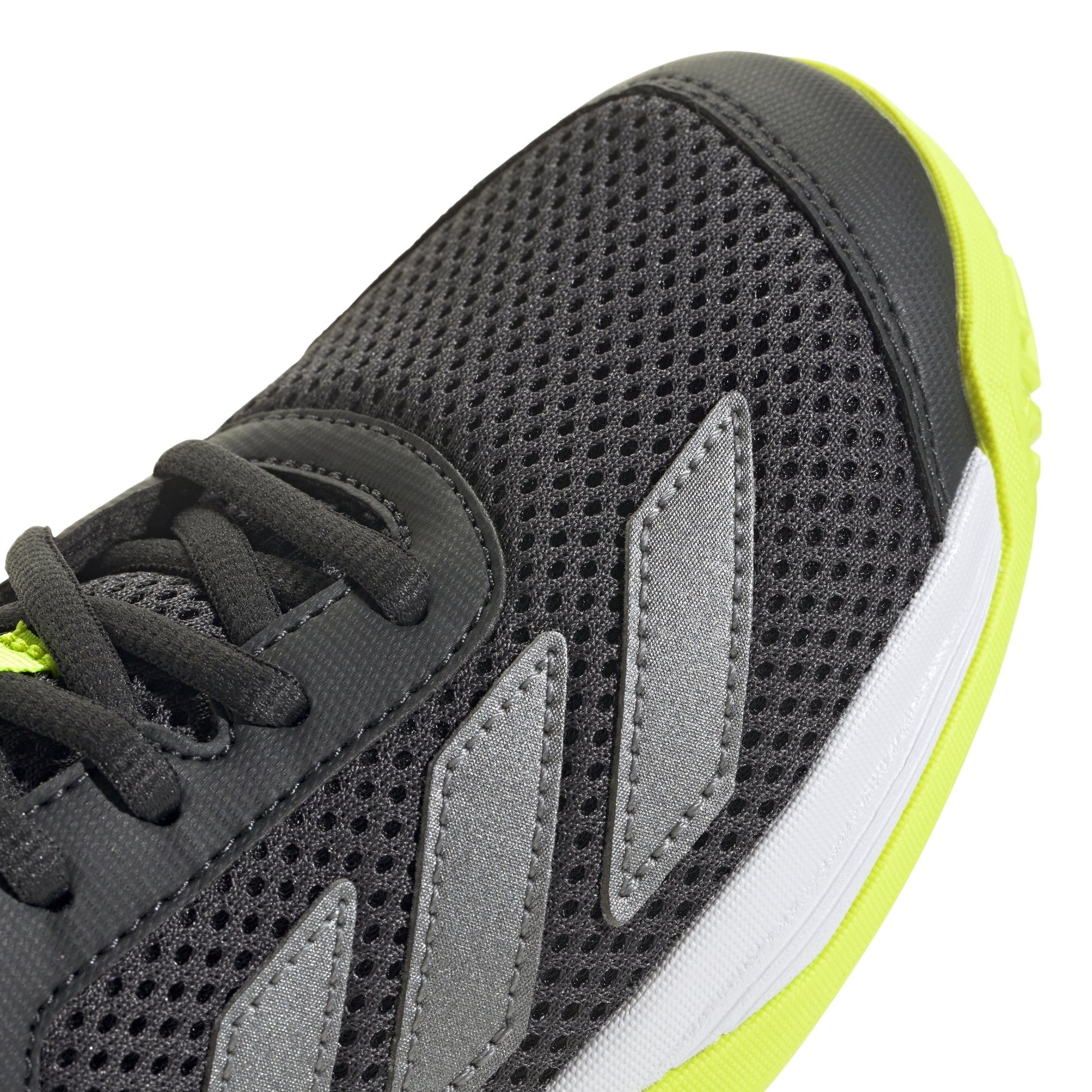 Black Adidas tennis shoe with black laces and yellow sole on a white background