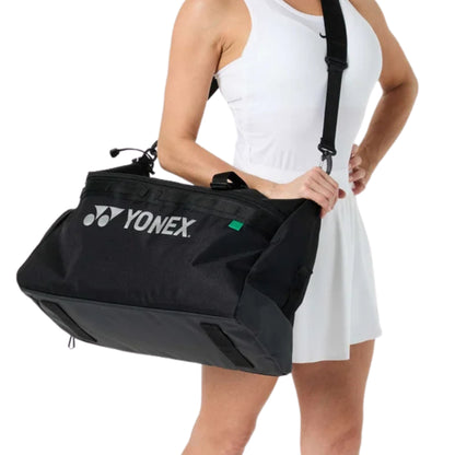 Person holding a black Yonex bag on a white background