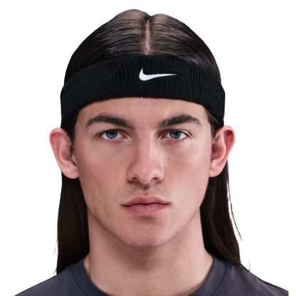 Person wearing a black Nike headband on a white background