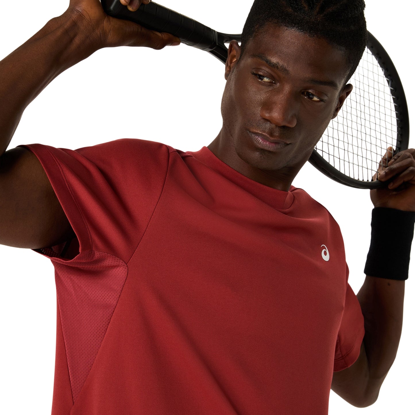 Person wearing a red Asics shirt with a logo, holding a tennis racket on a white background