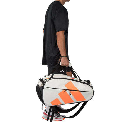 Person holding a white and orange sports bag with Adidas logo on a white background
