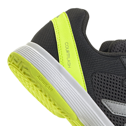 Close-up of a black and gray Adidas tennis shoe with yellow accents on a white background
