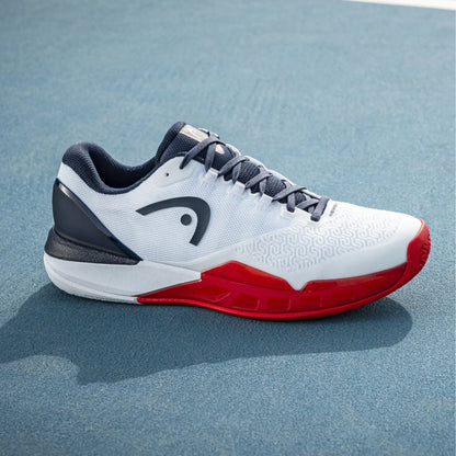White Head tennis shoe with red sole on a blue court