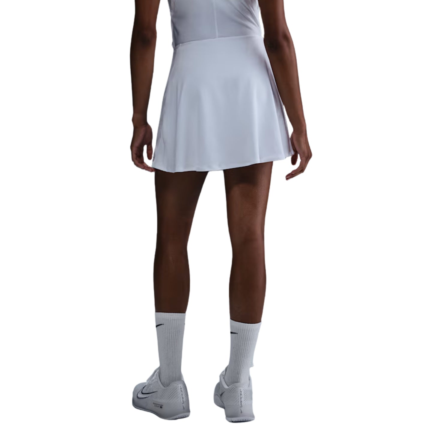 Person wearing a white tennis skirt, white socks, and white shoes on a white background