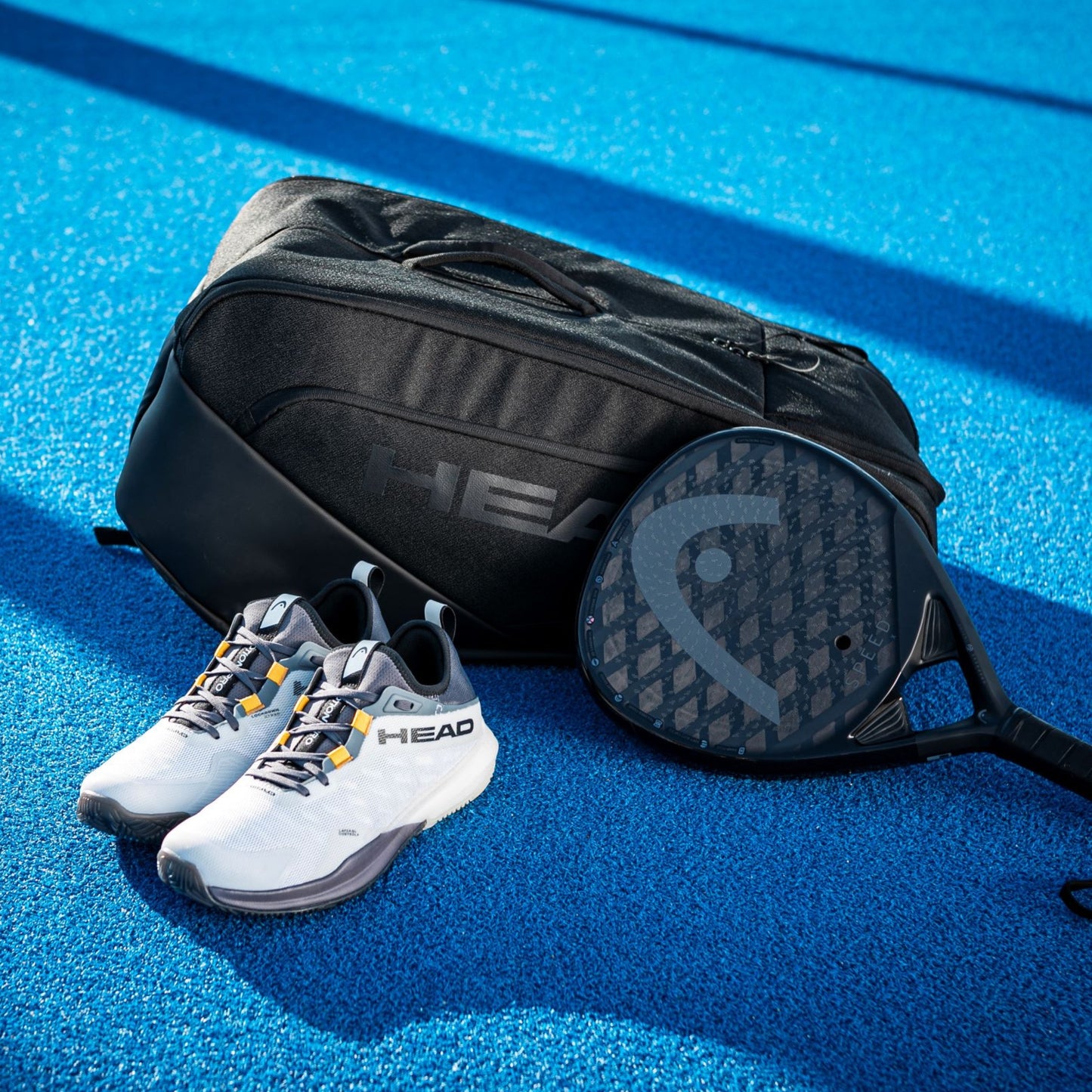 Tennis shoes, bag, and racket on a blue court