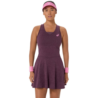 A woman wearing a sleeveless athletic dress in a dusty plum purple color with a tonal wavy pattern, paired with a pink visor and matching pink wristbands. The Asics logo is visible on the chest.
