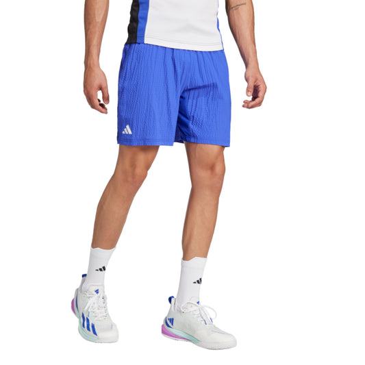 Person wearing blue Adidas shorts on a white background