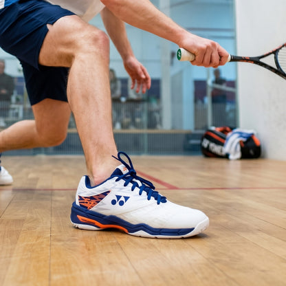 Person playing squash with focus on white and blue athletic shoe