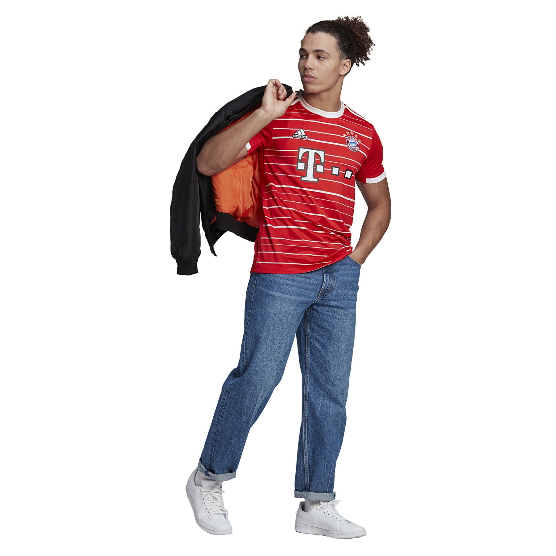 Person wearing an Adidas red sports jersey with visible branding, holding a jacket, on a white background