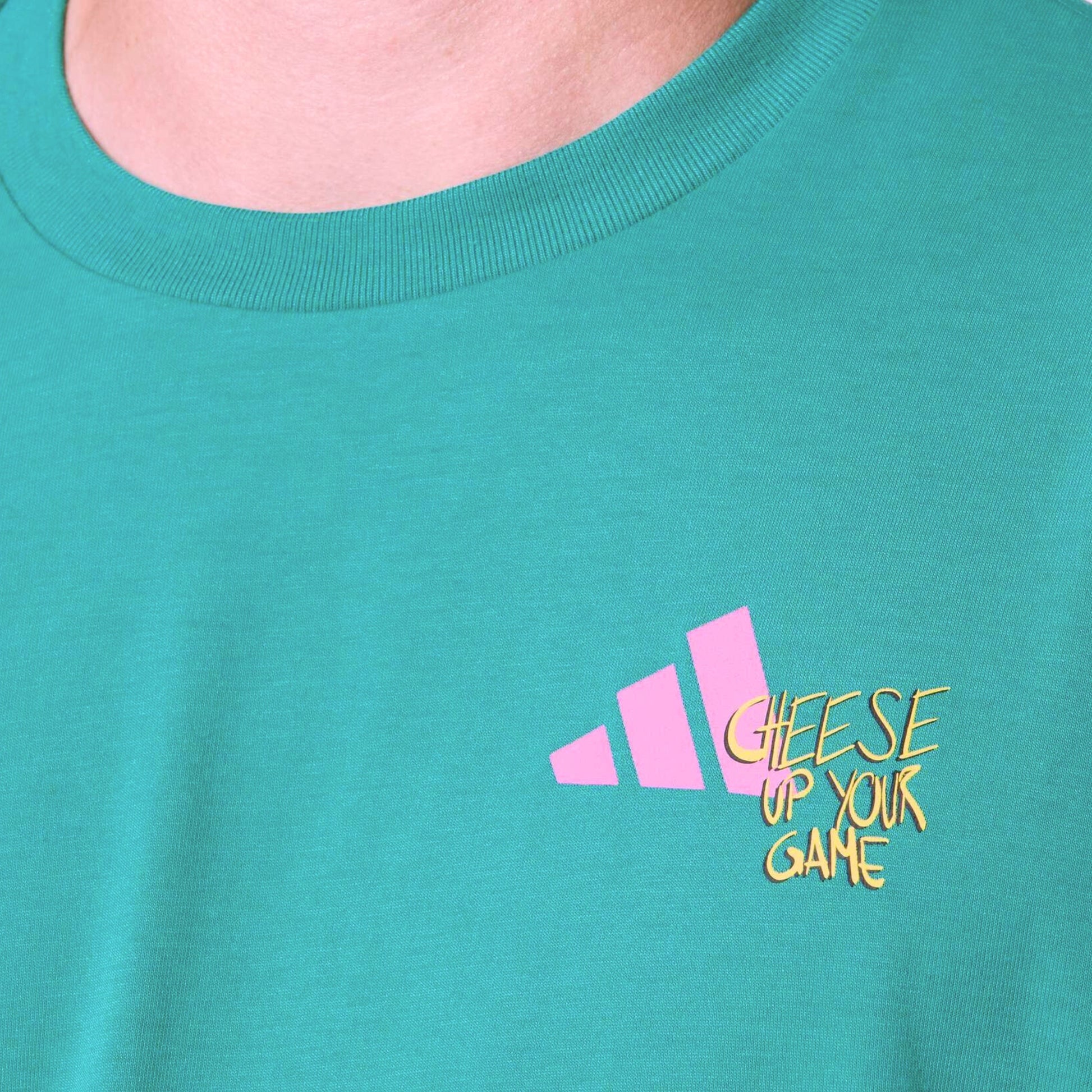 Close-up of a teal shirt wih a adiddas logo and wording cheese up your game