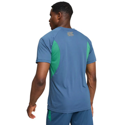 Person wearing a blue Puma soccer jersey shirt with green accents on a white background