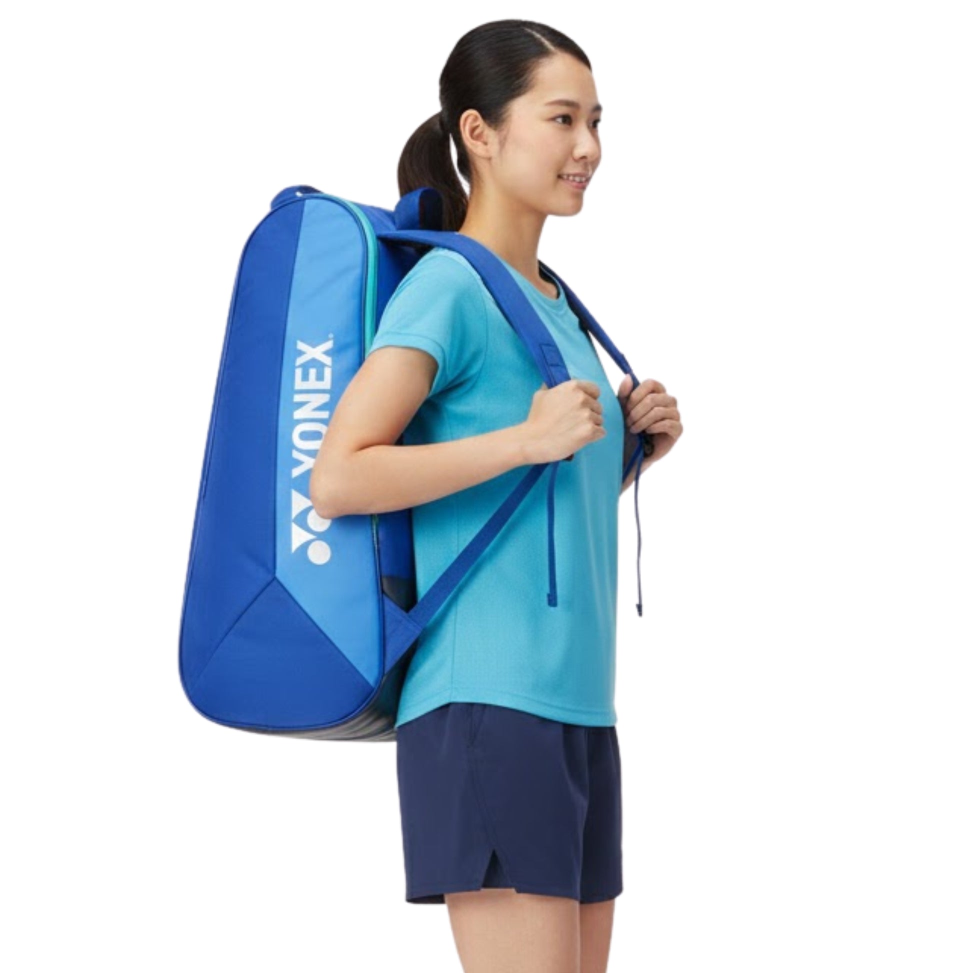 Woman carrying a blue Yonex tennis bag on a white background