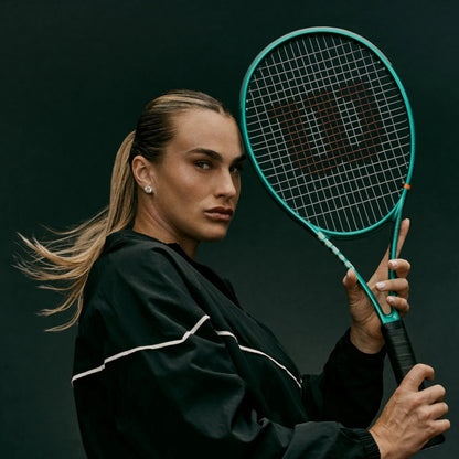 Person holding a tennis racket against a dark background
