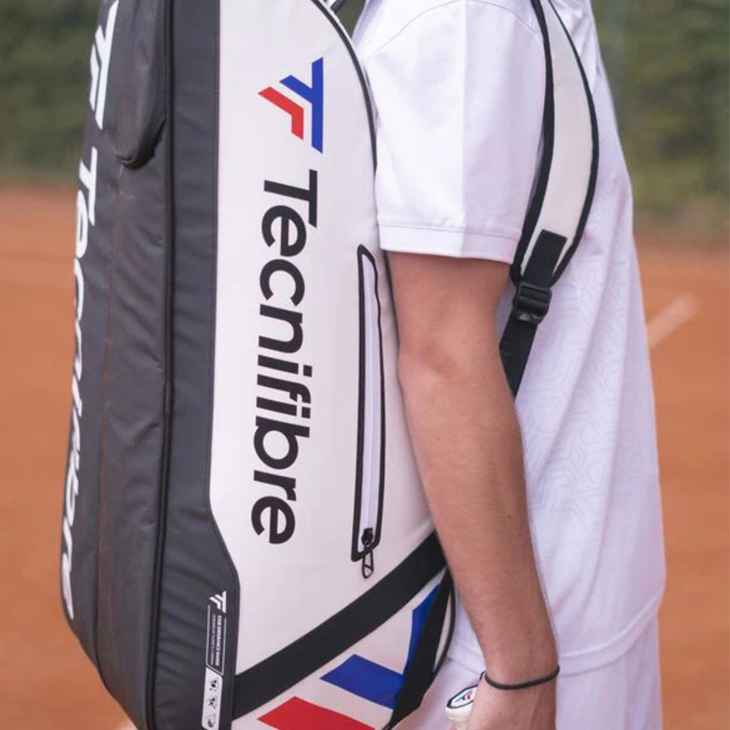 Person holding a Tecnifibre tennis racket bag on a tennis court