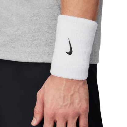 Person wearing a white wristband with a black logo on a neutral background