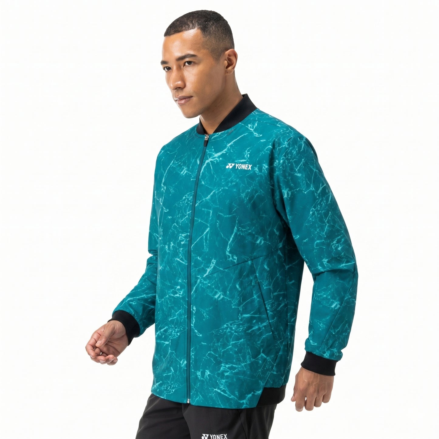 Man wearing a teal Yonex jacket on a white background