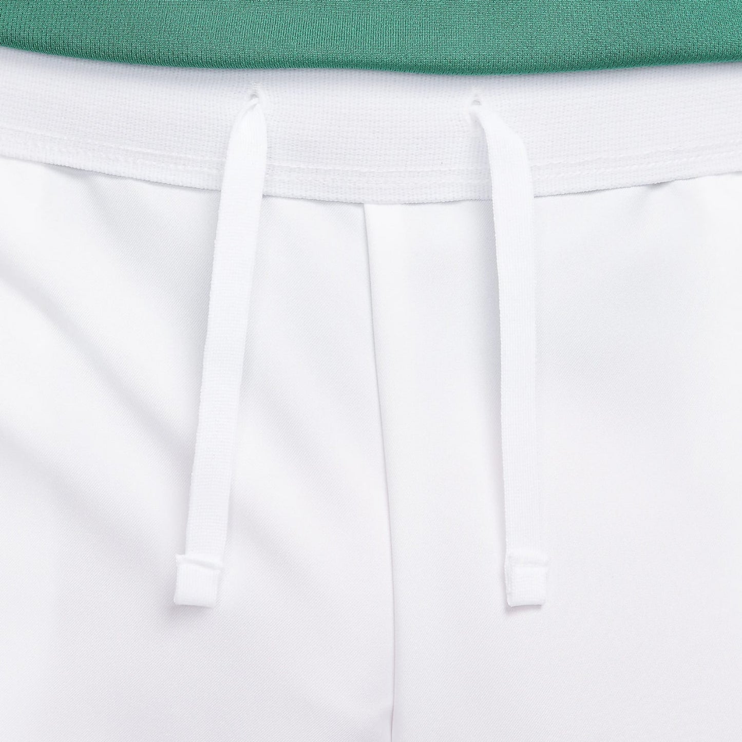 Close-up of white shorts with a green top on a light gray background